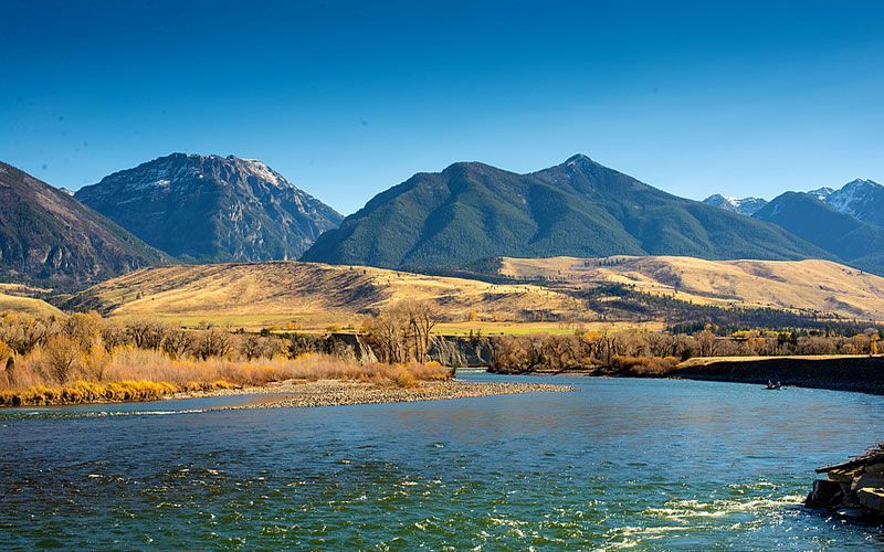 A river flowing through a mountainous area with mountains in the background.