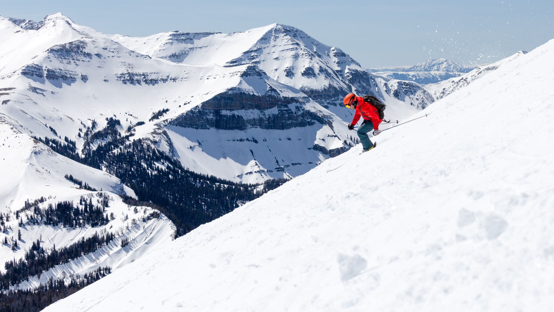 A person in a red jacket is skiing down a snowy mountain