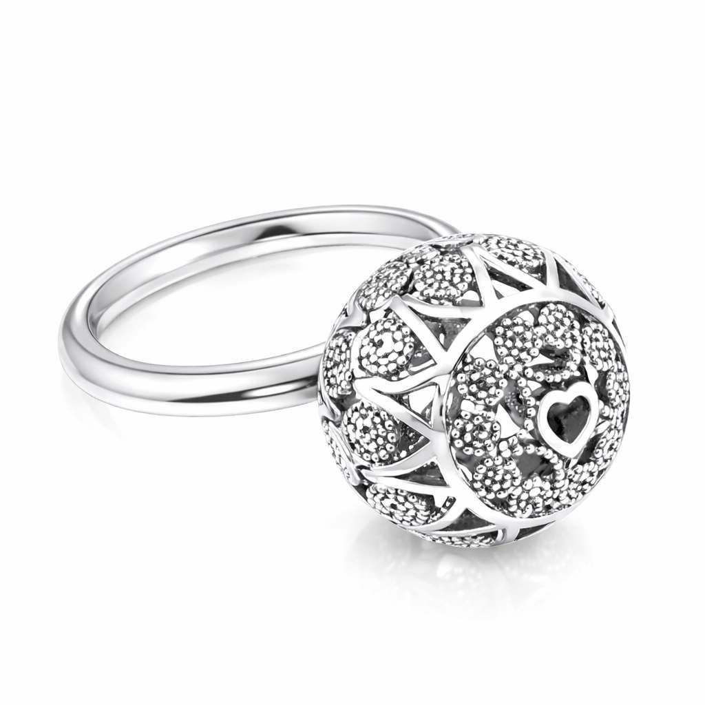 Anello in argento con motivo a cuore e parte superiore rotonda testurizzata su sfondo bianco.