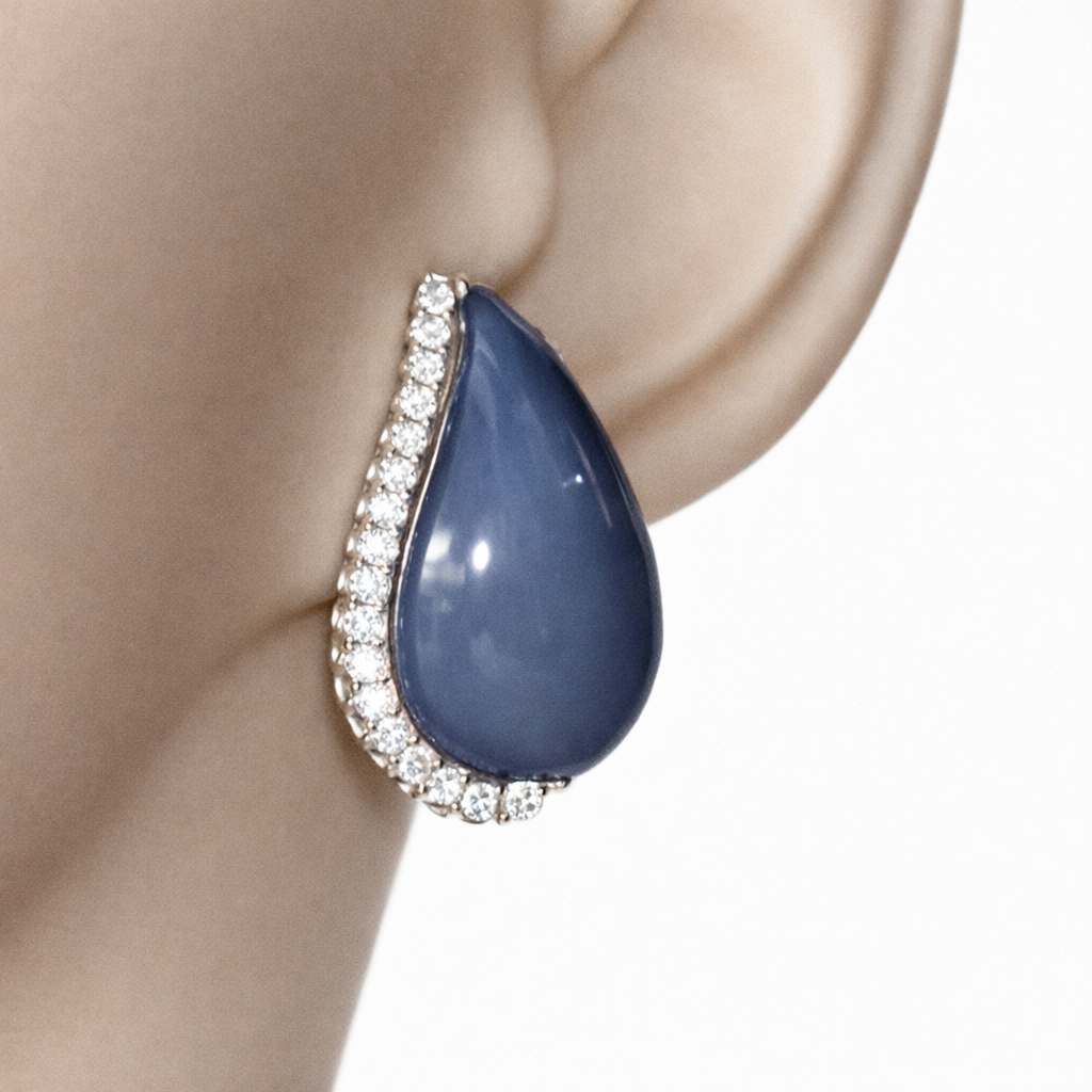 Orecchino a goccia con gemma blu e bordo tempestato di diamanti all'orecchio di una modella.