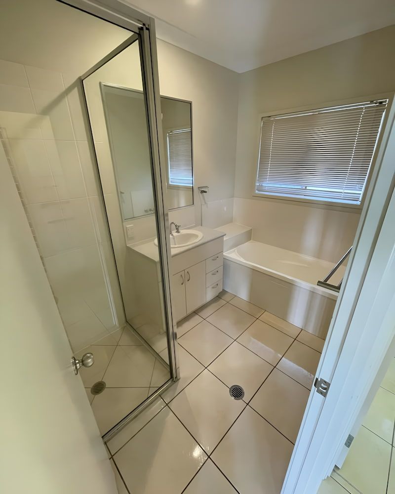 A Bathroom With A Sink, Tub, Shower And Mirror — Glittering Cleaning Service In Townsville, QLD