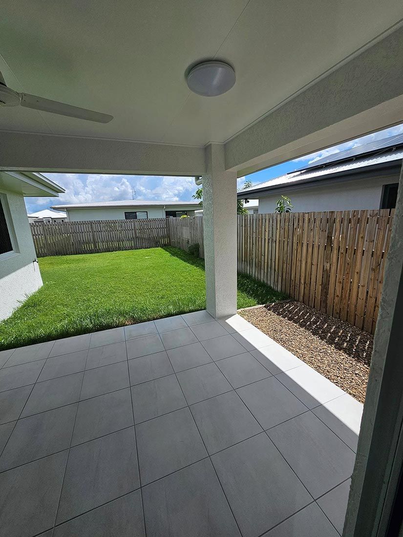 A Patio With a Ceiling Fan and a Fence in the Backyard of a House — Glittering Cleaning Service In Townsville, QLD