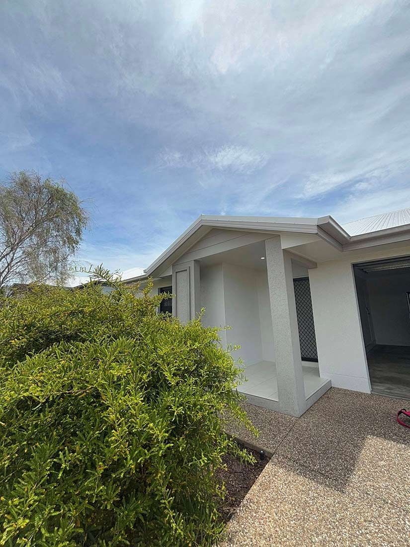 A White House With a Garage and a Bush in Front of It — Glittering Cleaning Service In Townsville, QLD