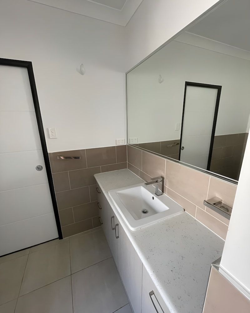 A Bathroom With A Sink And A Large Mirror — Glittering Cleaning Service In Townsville, QLD