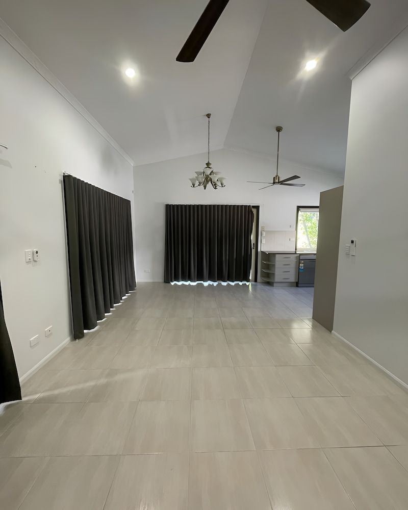 A Large Empty Room With A Ceiling Fan And Curtains — Glittering Cleaning Service In Townsville, QLD