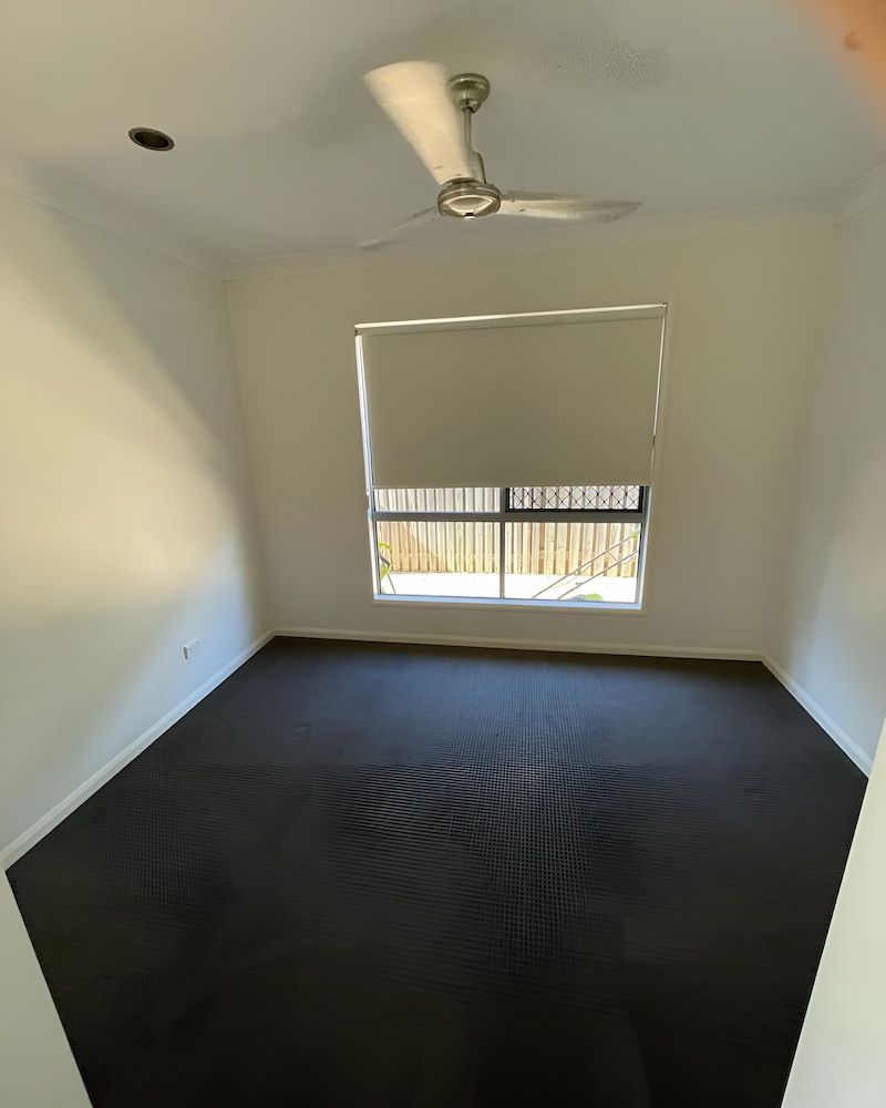 An Empty Bedroom With A Ceiling Fan And A Window — Glittering Cleaning Service In Townsville, QLD