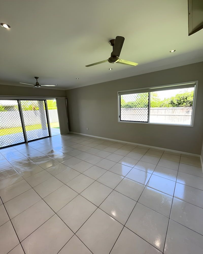 An Empty Living Room With A Ceiling Fan And Sliding Glass Doors — Glittering Cleaning Service In Townsville, QLD