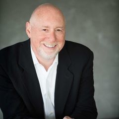 A man wearing black suit  and a white shirt is smiling for the camera.
