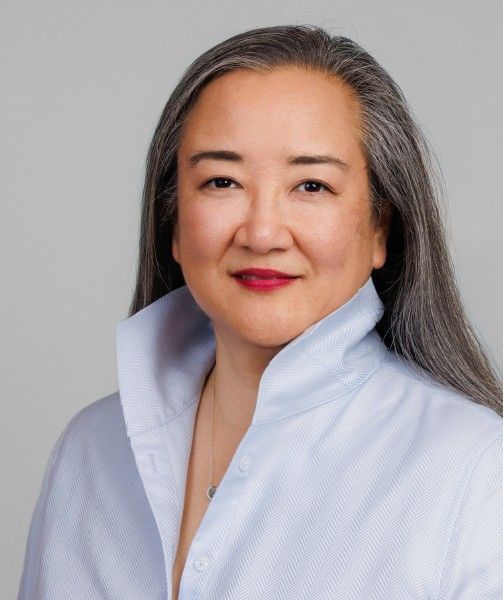 A woman with long brown hair is smiling for the camera