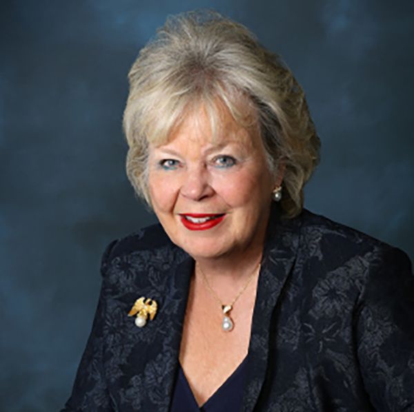 A woman with short blonde hair is  wearing a suit.