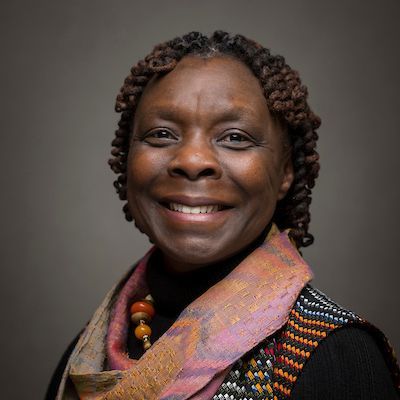A woman wearing a scarf and a necklace is smiling for the camera.