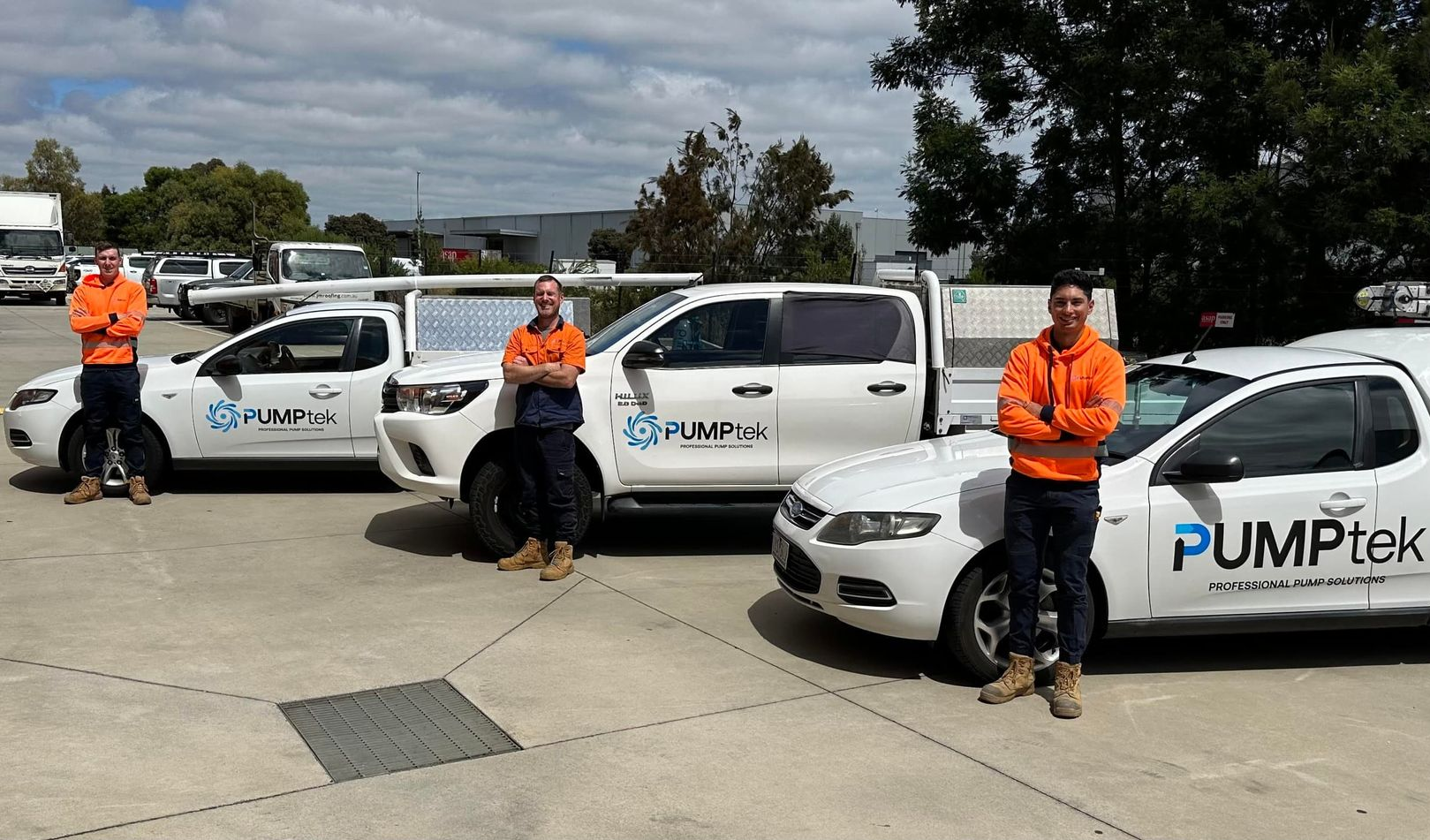Two white PumpWell service cars parked outside a dark gray industrial building on a sunny day — PUMPtek in Grovedale, VIC