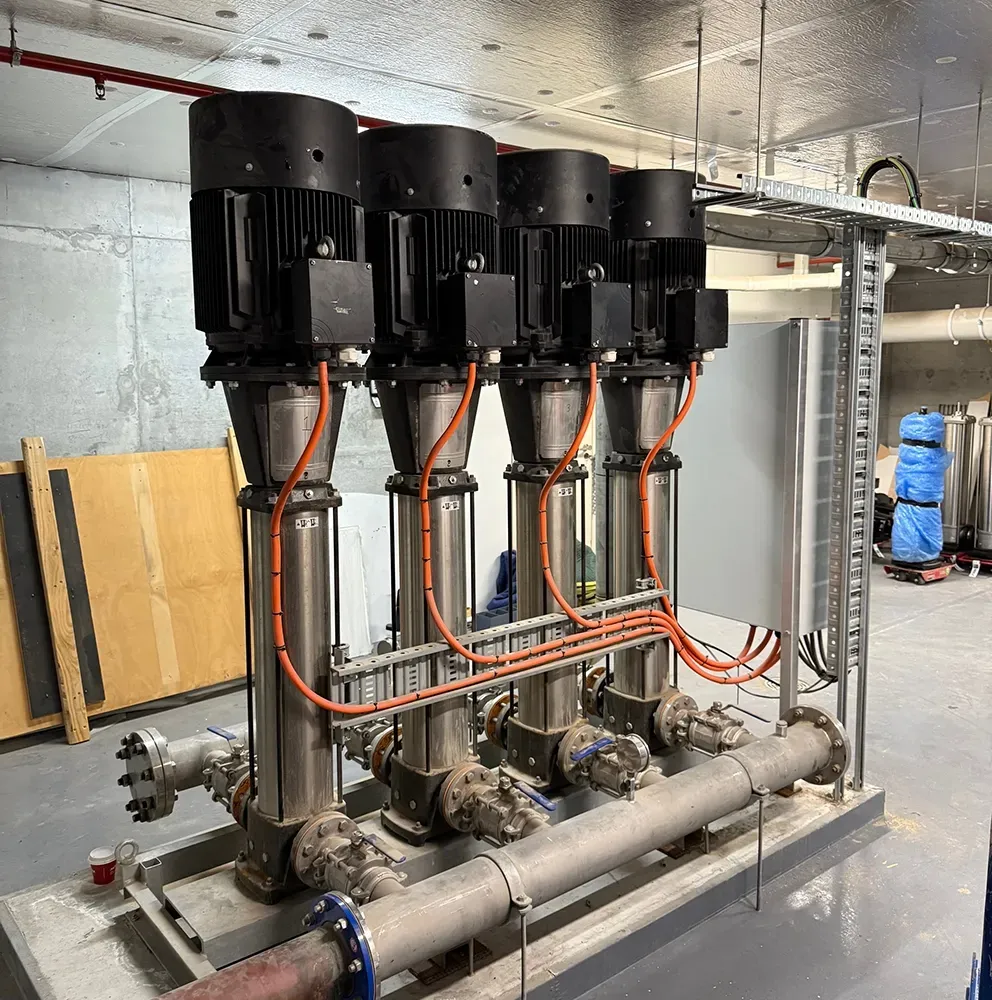Four black pump motors on a metal skid with stainless piping in an industrial room  — PUMPtek in Bendigo, VIC