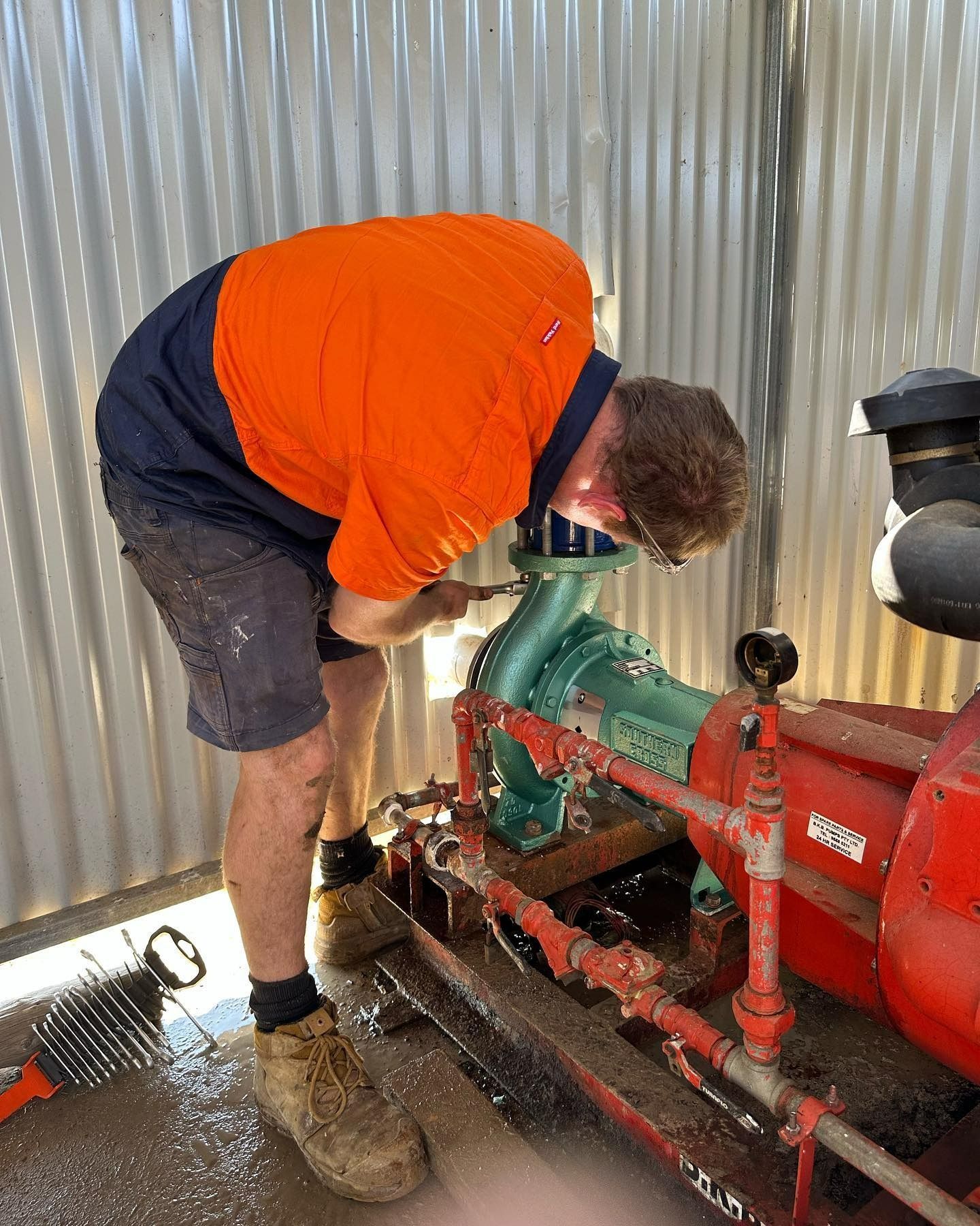 Worker in Orange Shirt Repairs a Pump, Spraying Water — PUMPtek in Grovedale, VIC