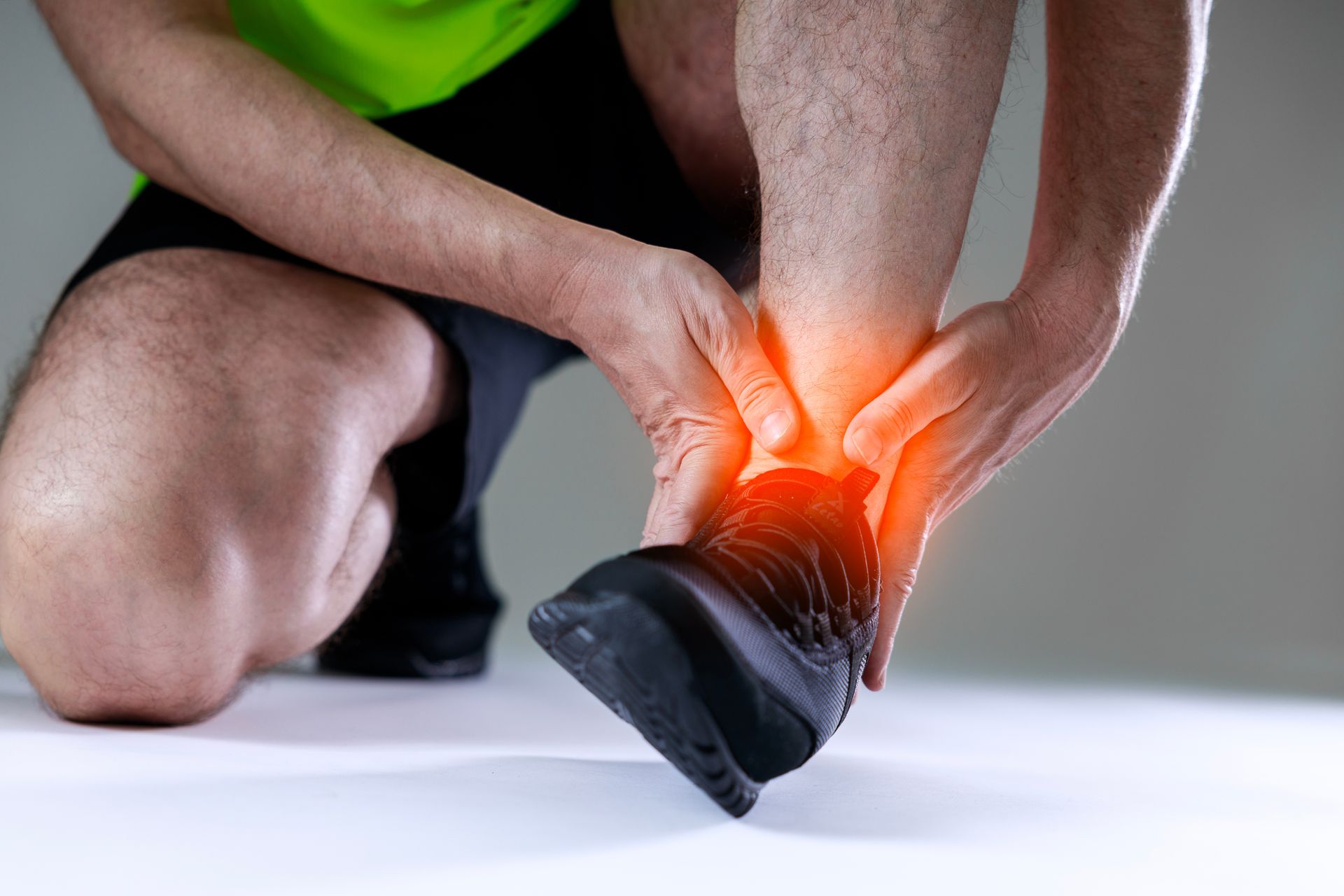 Person holding their ankle, indicating pain; red glow highlights the injury.