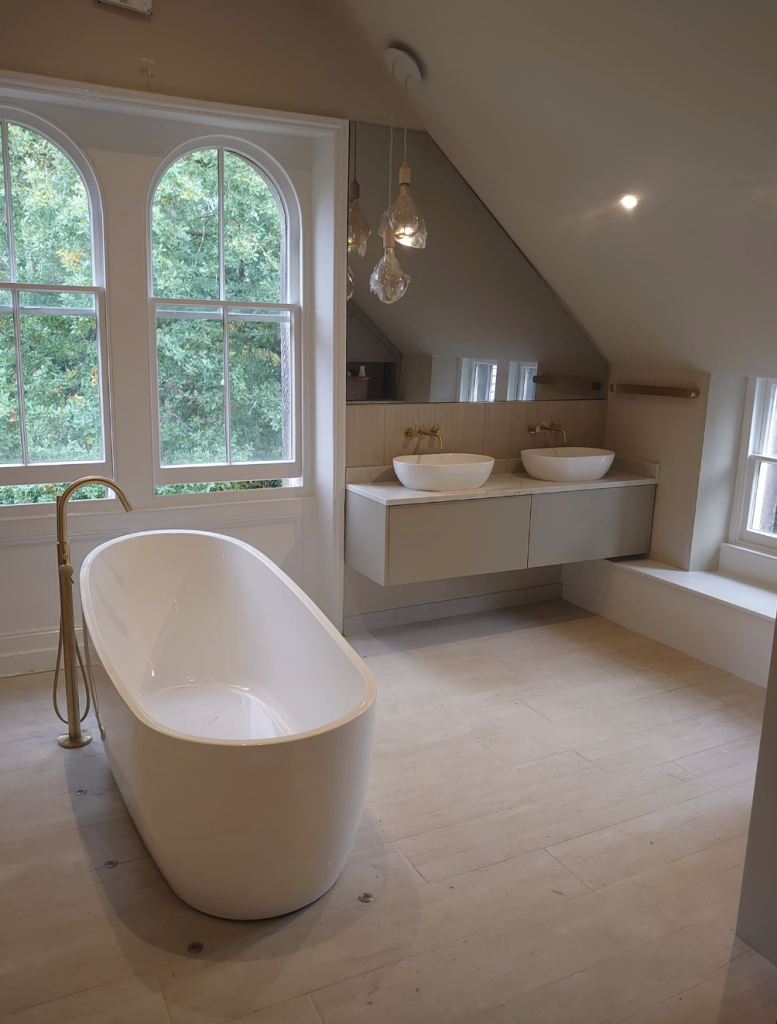 A modern bathroom with a freestanding white tub, dual vessel sinks on a floating vanity, and arched windows.