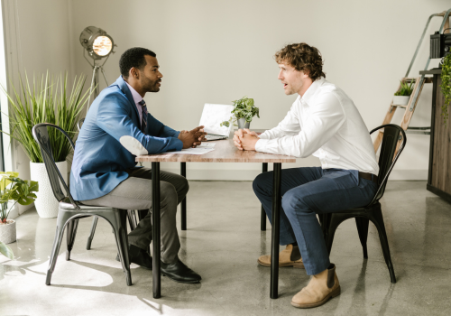 Two men in a meeting scenario facing each other at a table