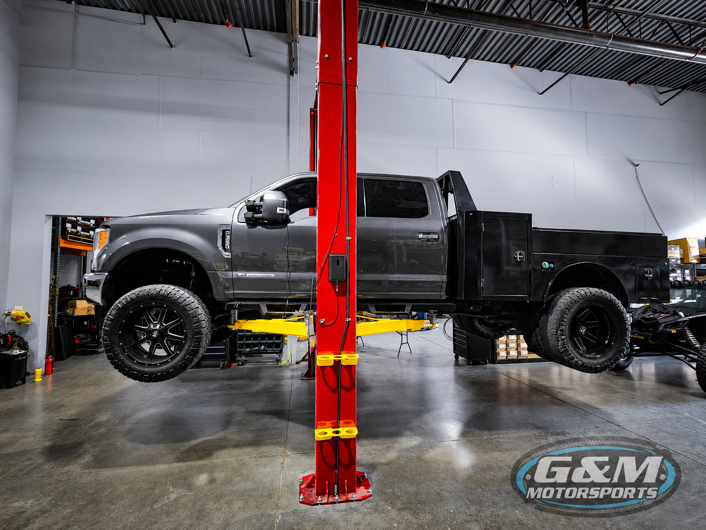 Trucks On Hydraulic Lifts Inside Service Bay | G & M Motorsports