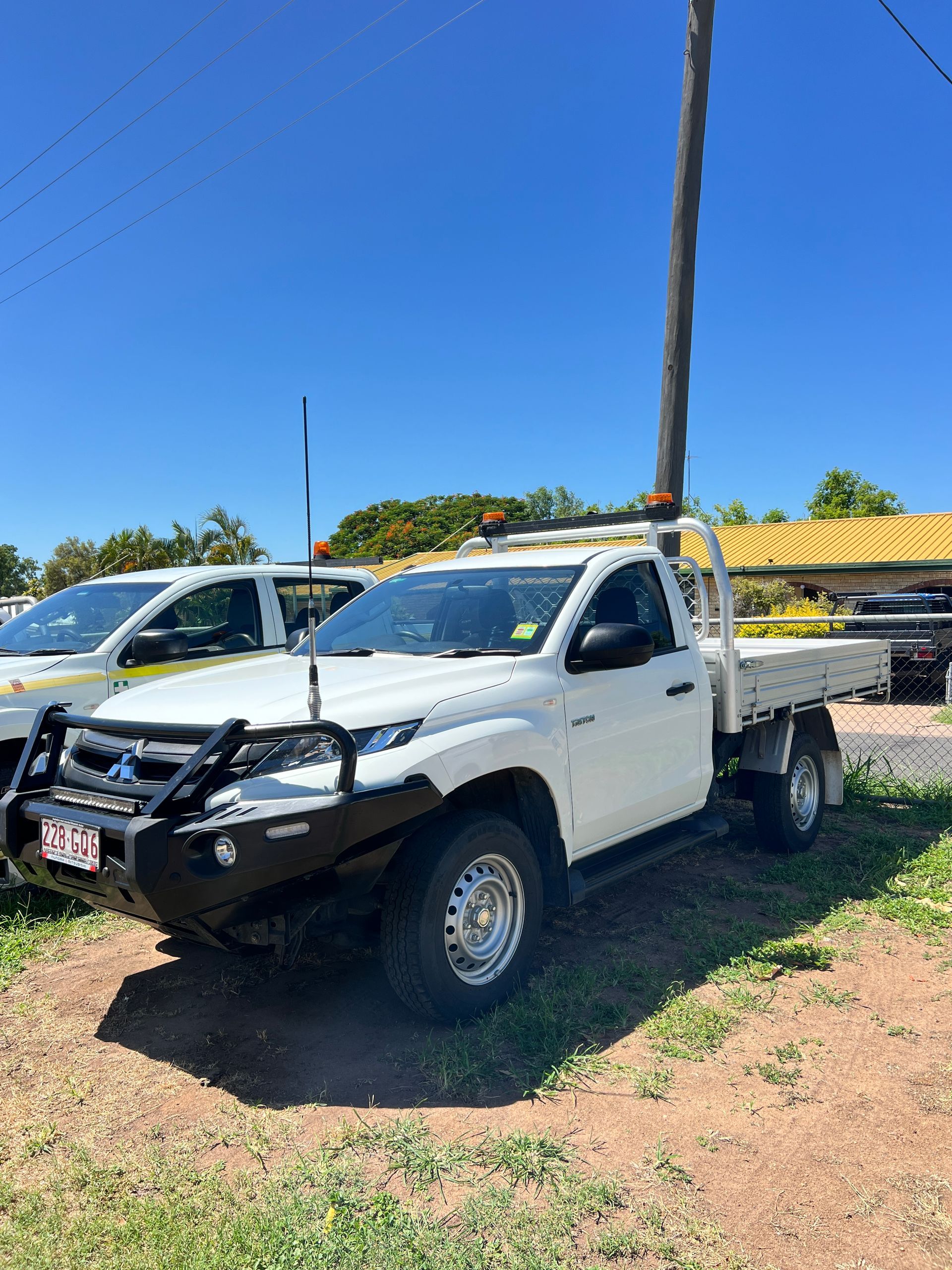 A White Truck With A Flat Bed Is Parked In A Grassy Field — Locqal Car Truck Trailer Rentals in Emerald, QLD