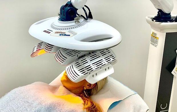 A Person Is Laying On A Bed With A Machine On Their Head — Aura Mediclinic In Ashmore, QLD