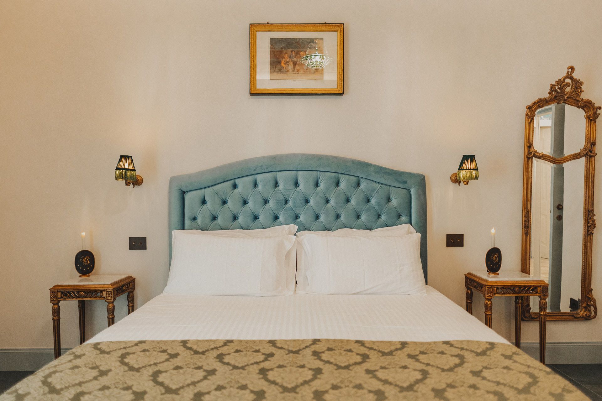 Elegante camera da letto con testiera imbottita color verde acqua,e specchio a figura intera con decorazioni elaborate.