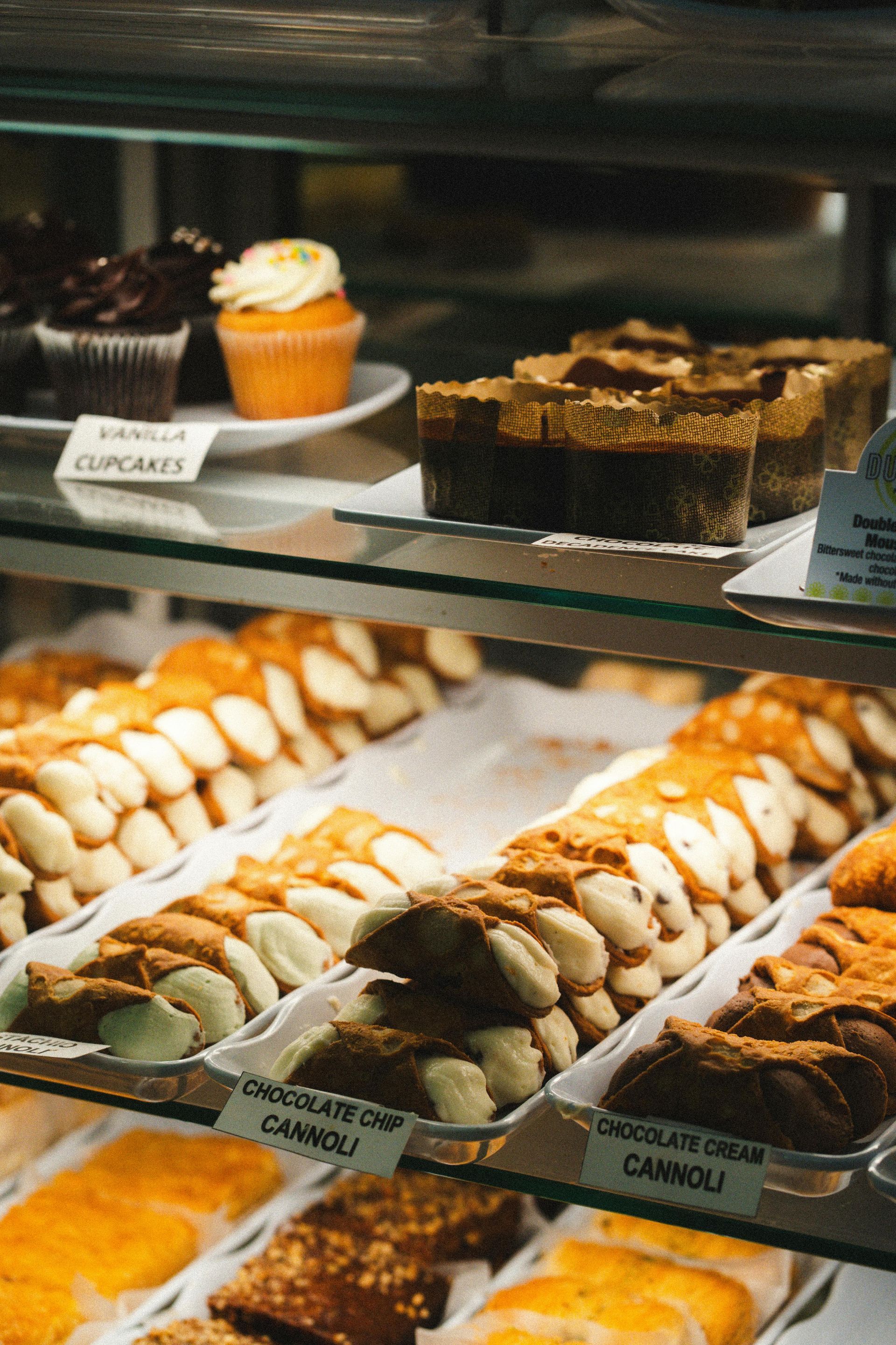 Vetrina di pasticceria con cupcake, cannoli e dolci assortiti in una pasticceria