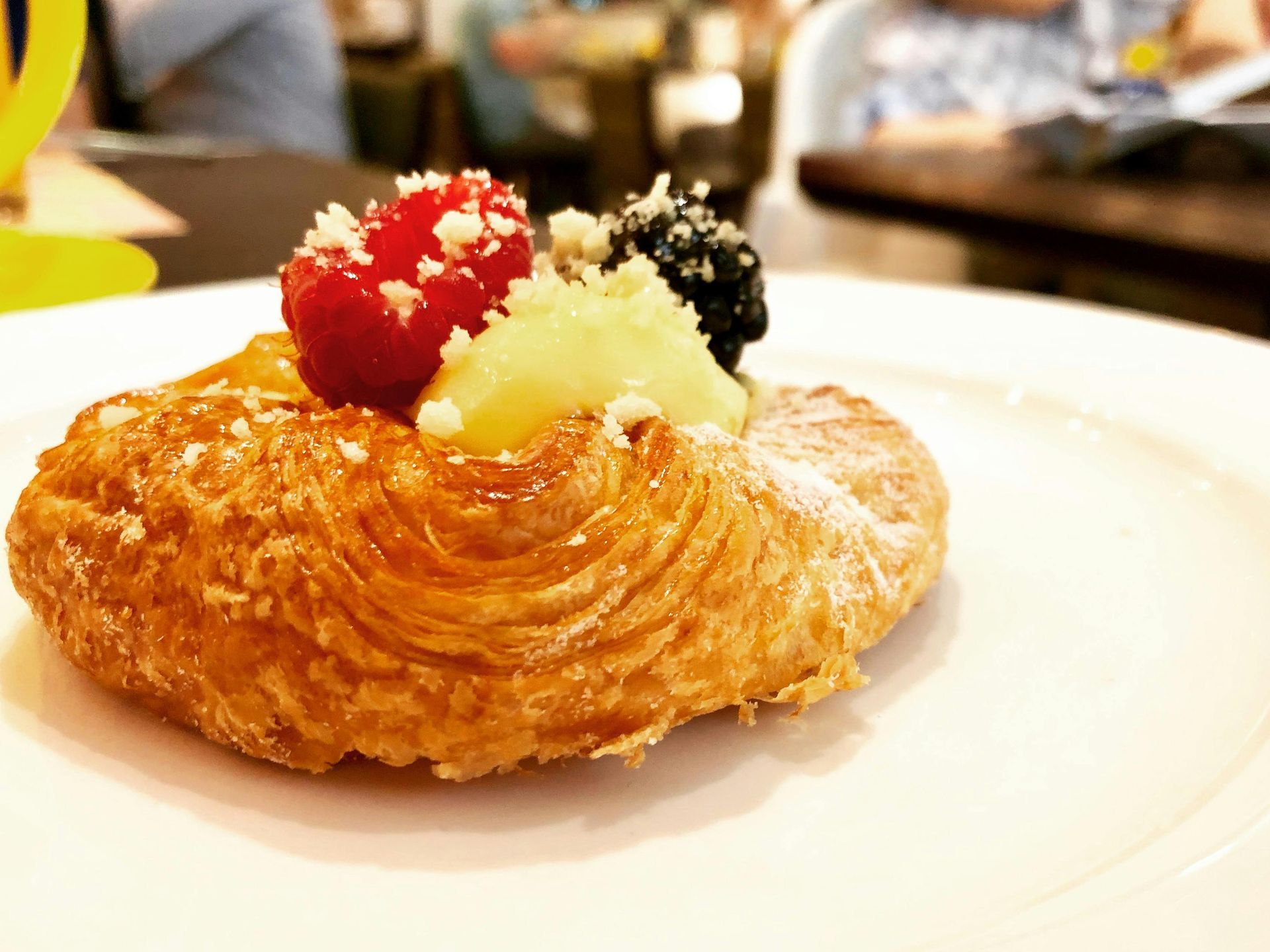 Pasticcino guarnito con crema rossa, bianca e nera su un piatto bianco