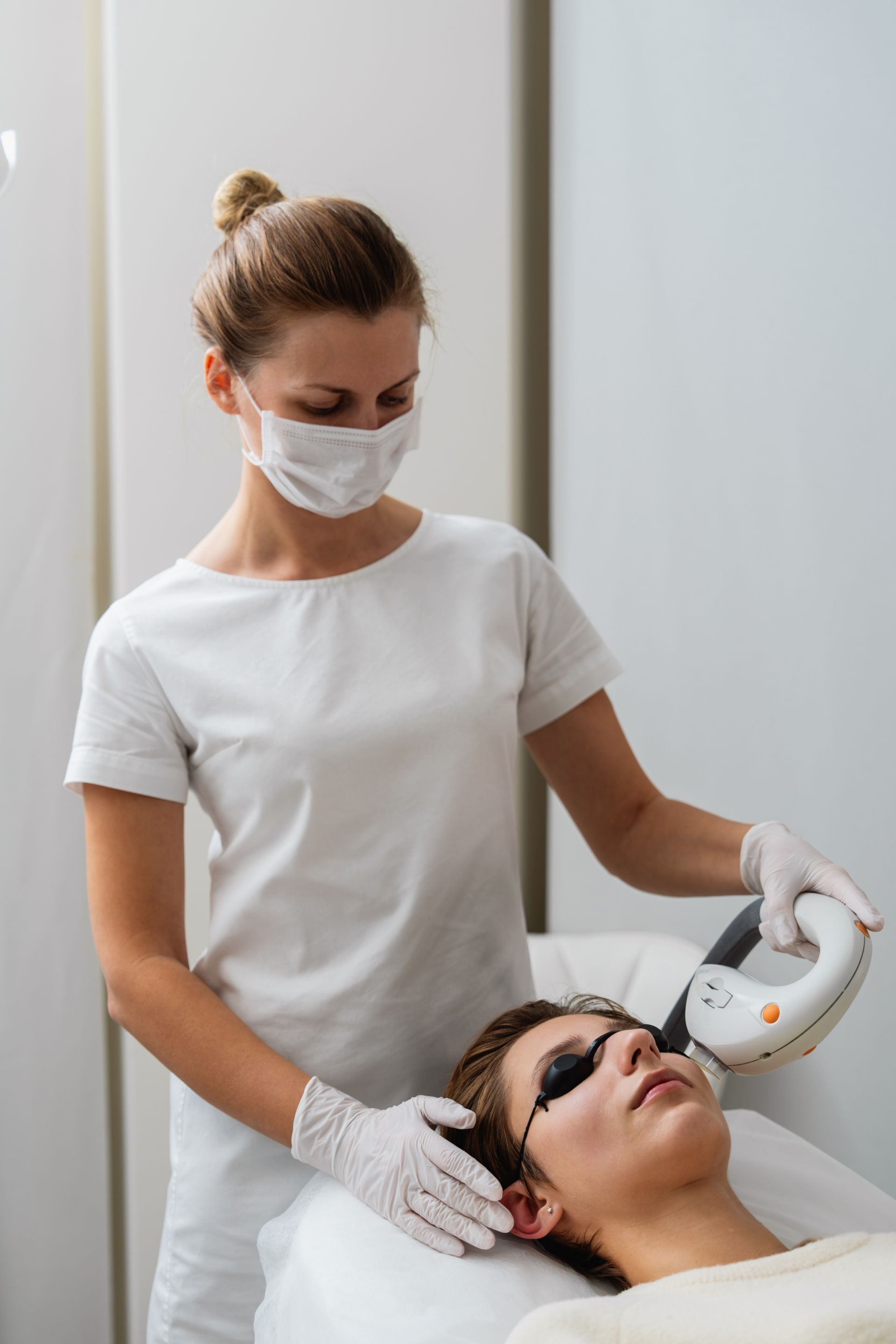 A woman is giving a man a laser treatment on his face.