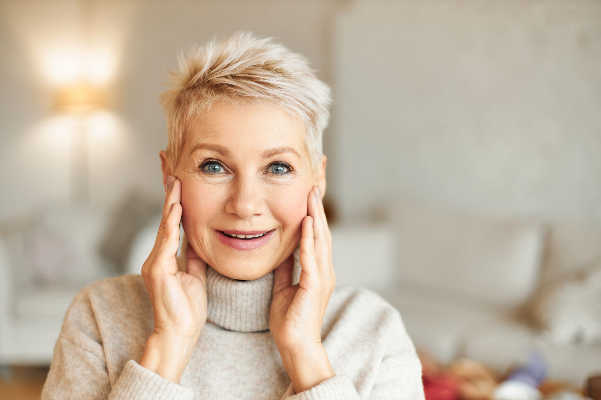 A woman is smiling while holding a leaf in front of her face.