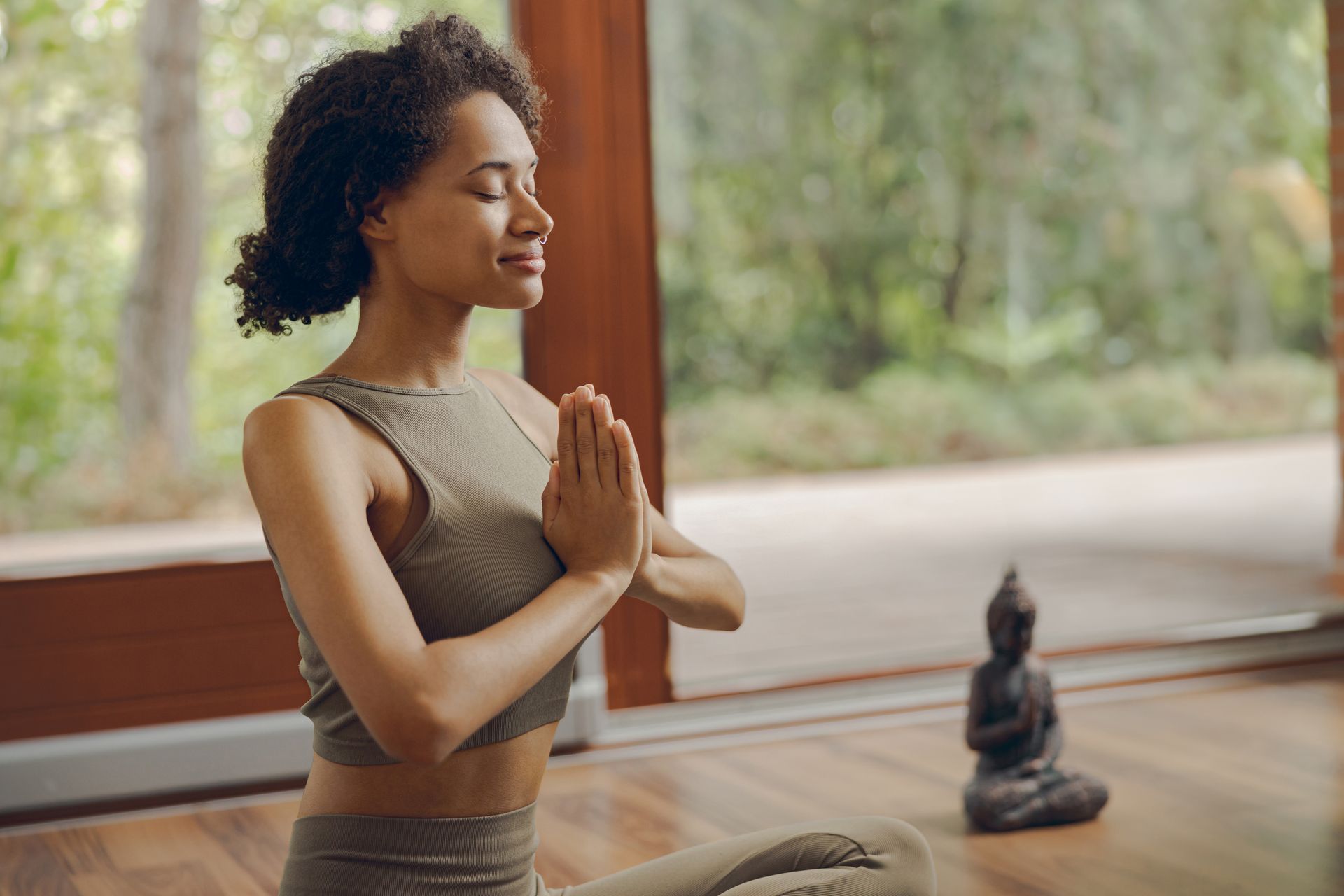 A woman is meditating in front of a window in a yoga studio.