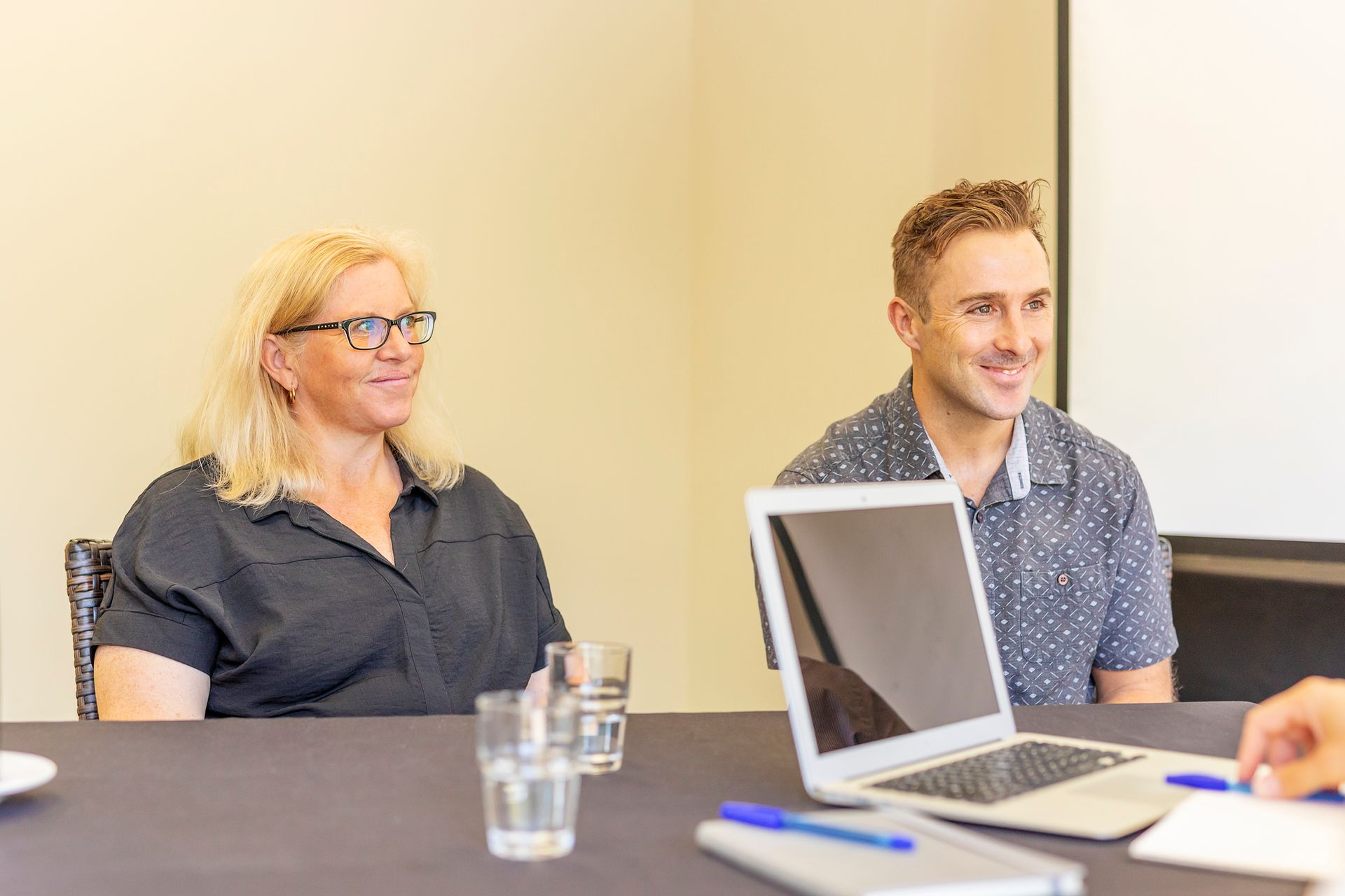 A man and a woman are sitting at a table with a laptop.