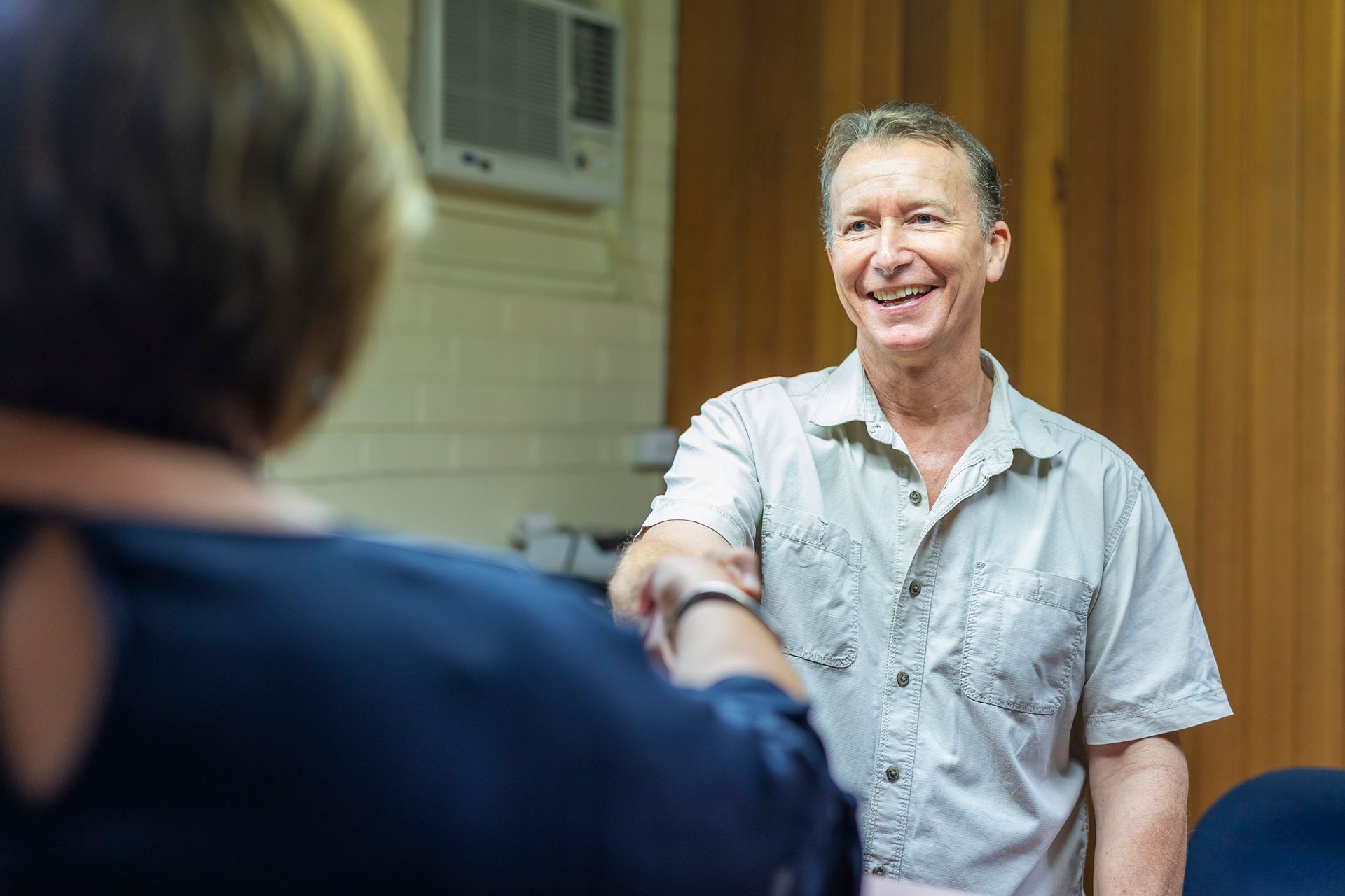 A man is shaking hands with a woman in a room.