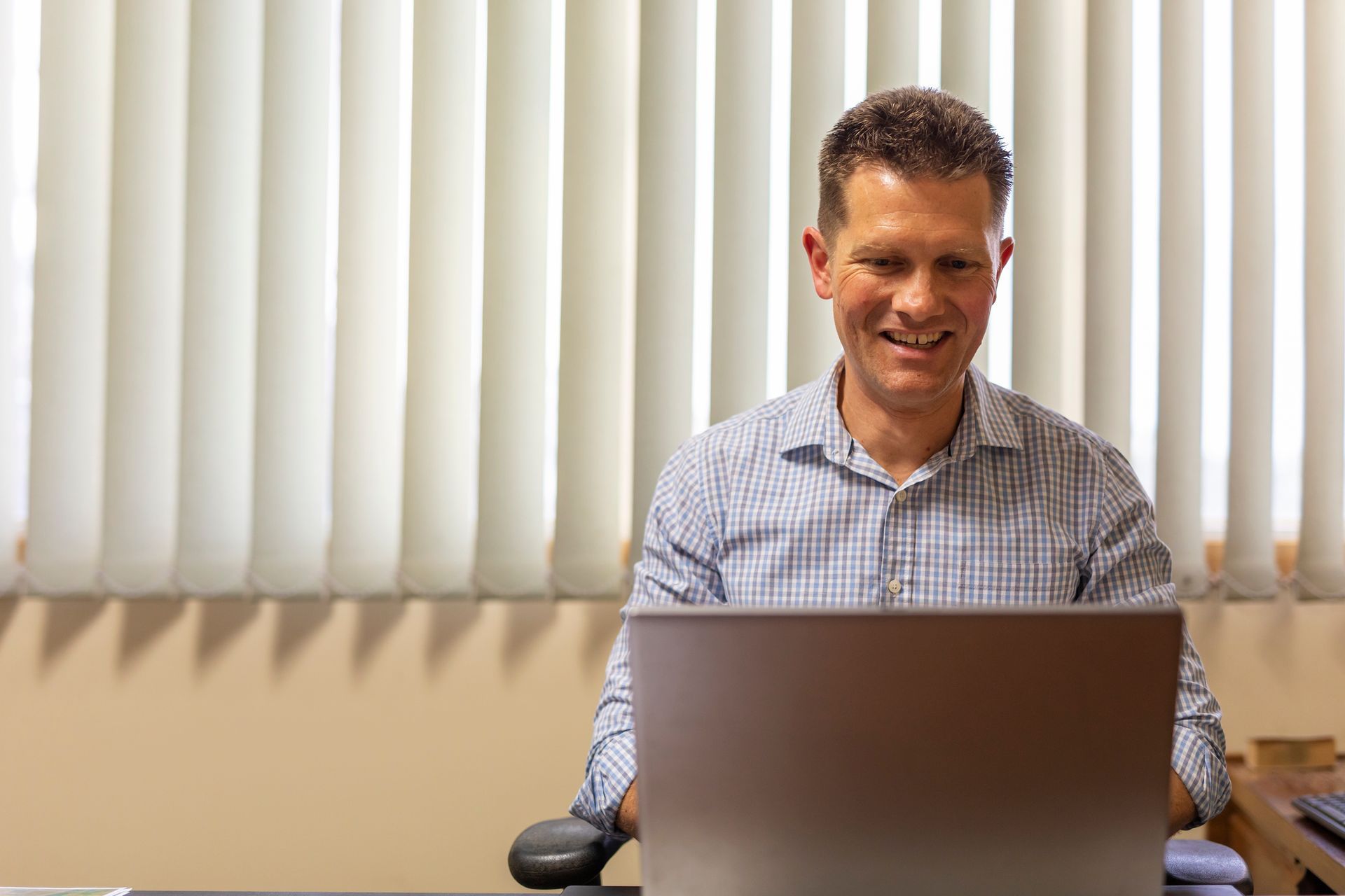 A man is sitting at a desk in front of a laptop computer.