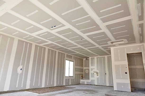 Drywall installation in a room, with unfinished walls and ceiling.