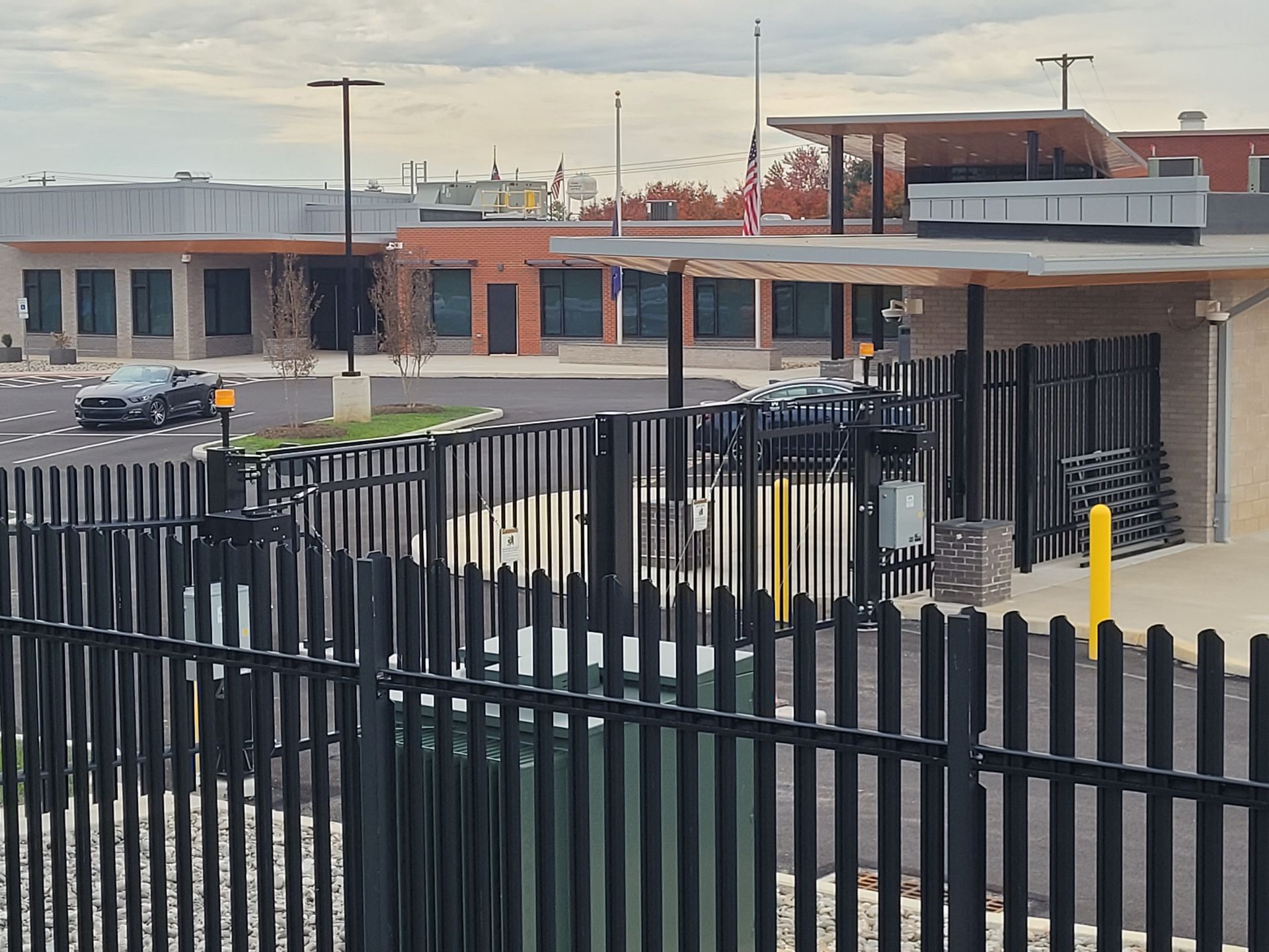 Industrial building and parking lot behind a black metal fence at dusk