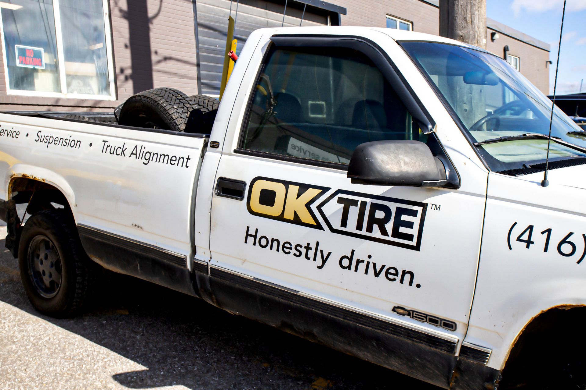 White OK Tire truck with tires in the bed, parked outside.