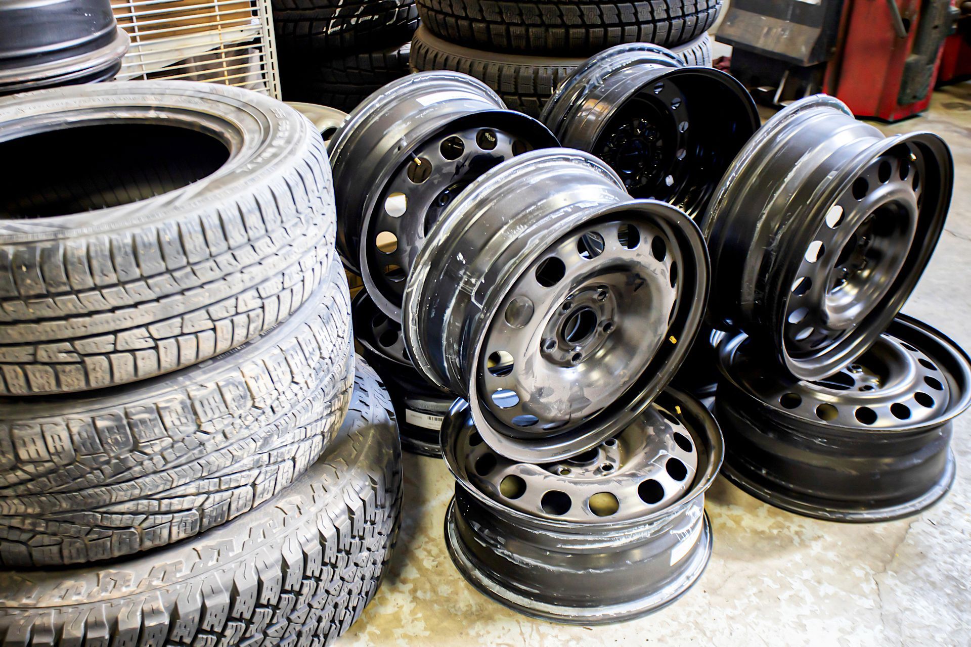 Stack of used tires and a pile of black steel wheels.