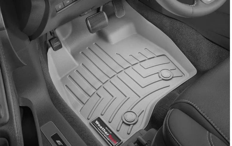 Gray car floor mat covering vehicle floor, around pedals.