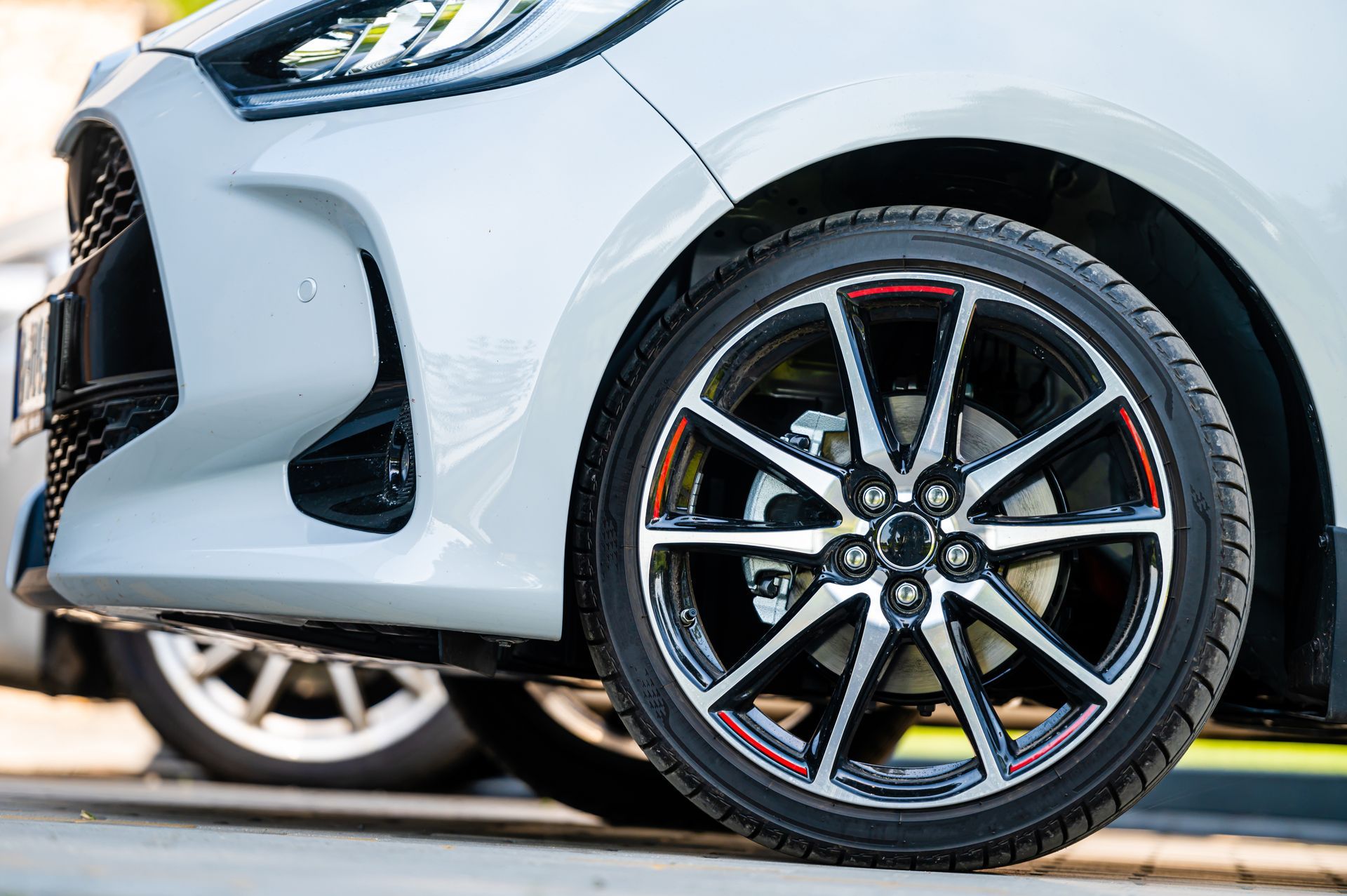 Close-up of a silver car’s front wheel and fender with a sporty alloy rim and red brake caliper