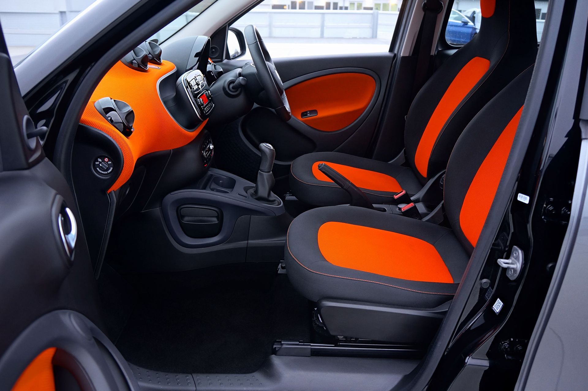 Luxury car interior with black dashboard and steering wheel, tan leather seat, and center console
