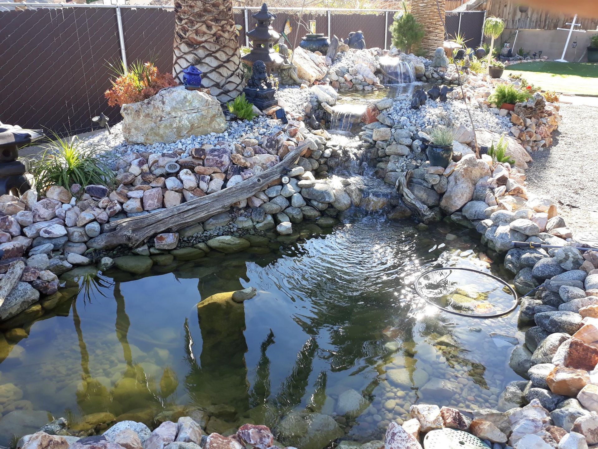 A pond surrounded by rocks and a waterfall in a backyard