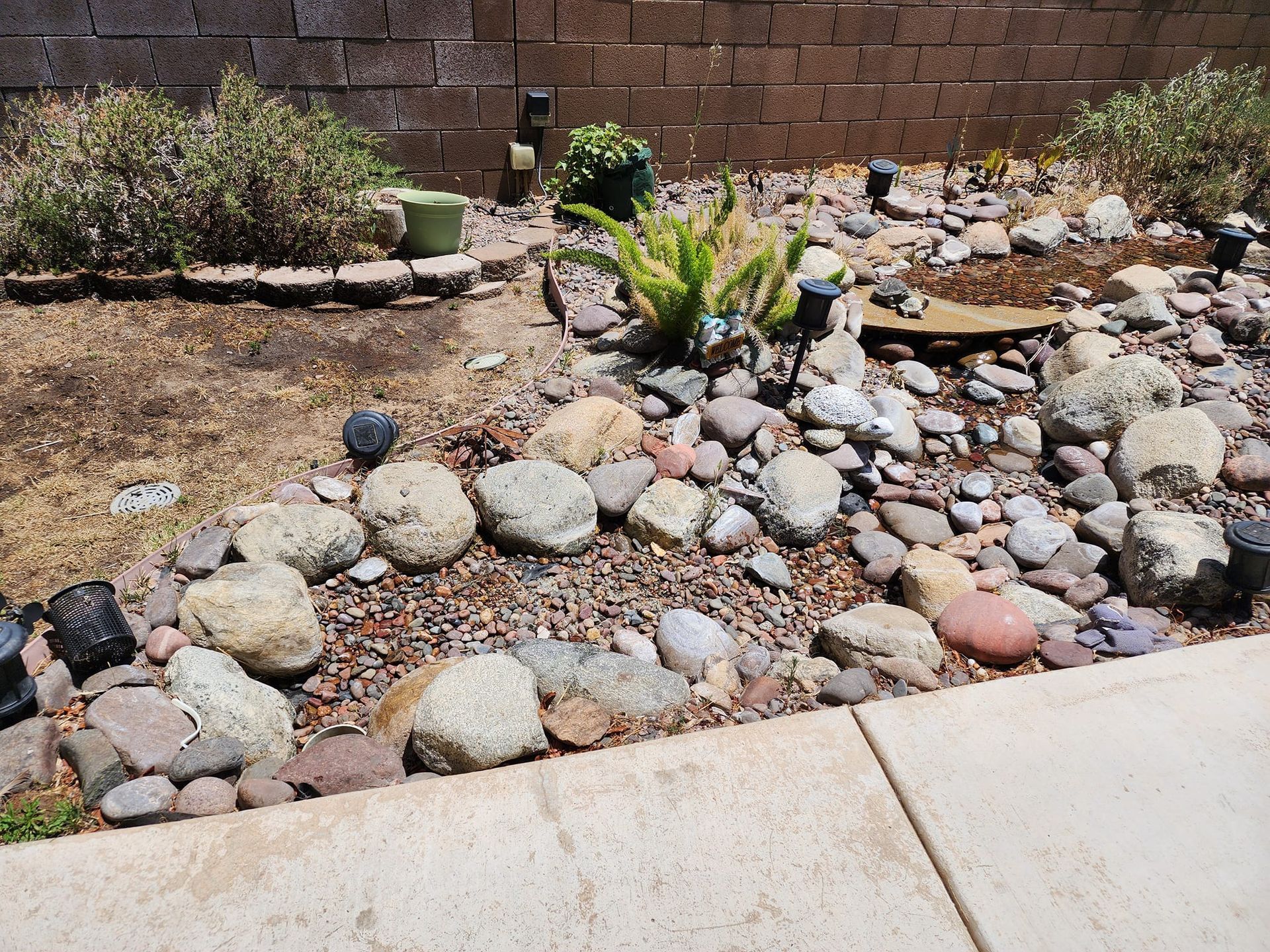 A rock garden with a brick wall in the background