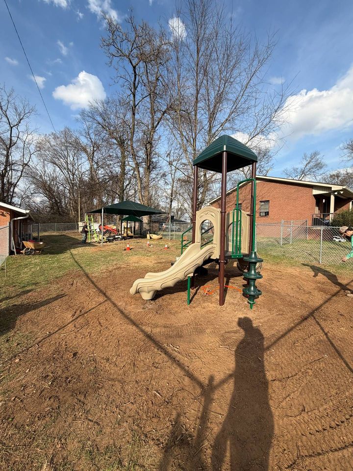 Backyard playground with slide, climbing tower, and swing set under a partly cloudy sky