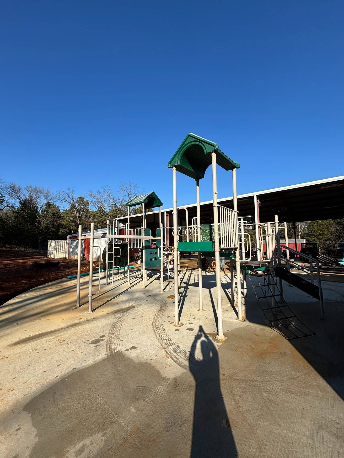 Outdoor playground with slides, climbing structures, and swings under a clear blue sky.