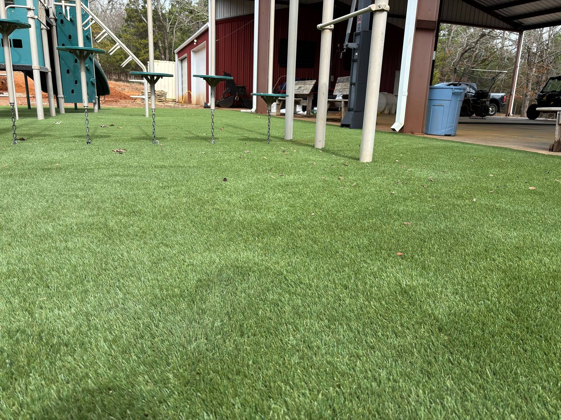 Grassy yard with playground equipment and a red building in the background