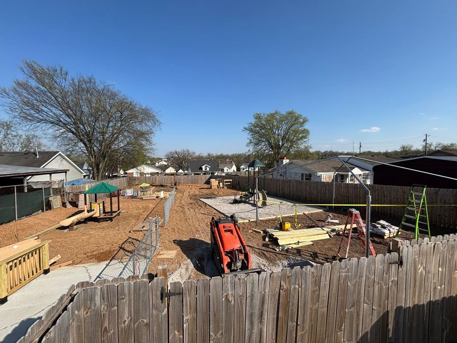 Construction site with excavators, building materials, and framed foundations in a residential neighborhood
