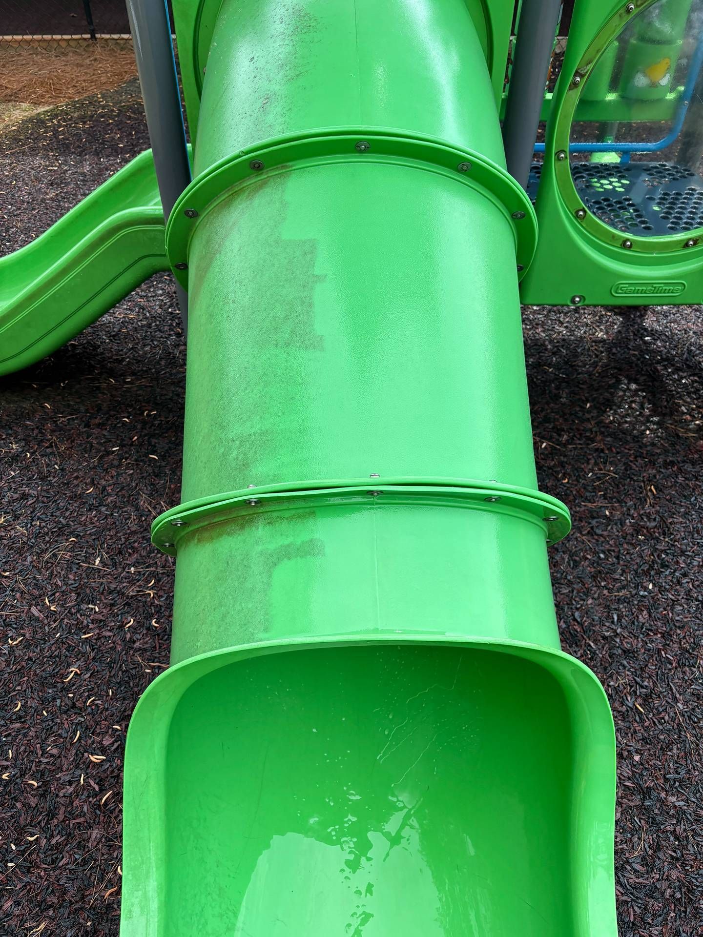 Bright green playground tube slide, close-up view