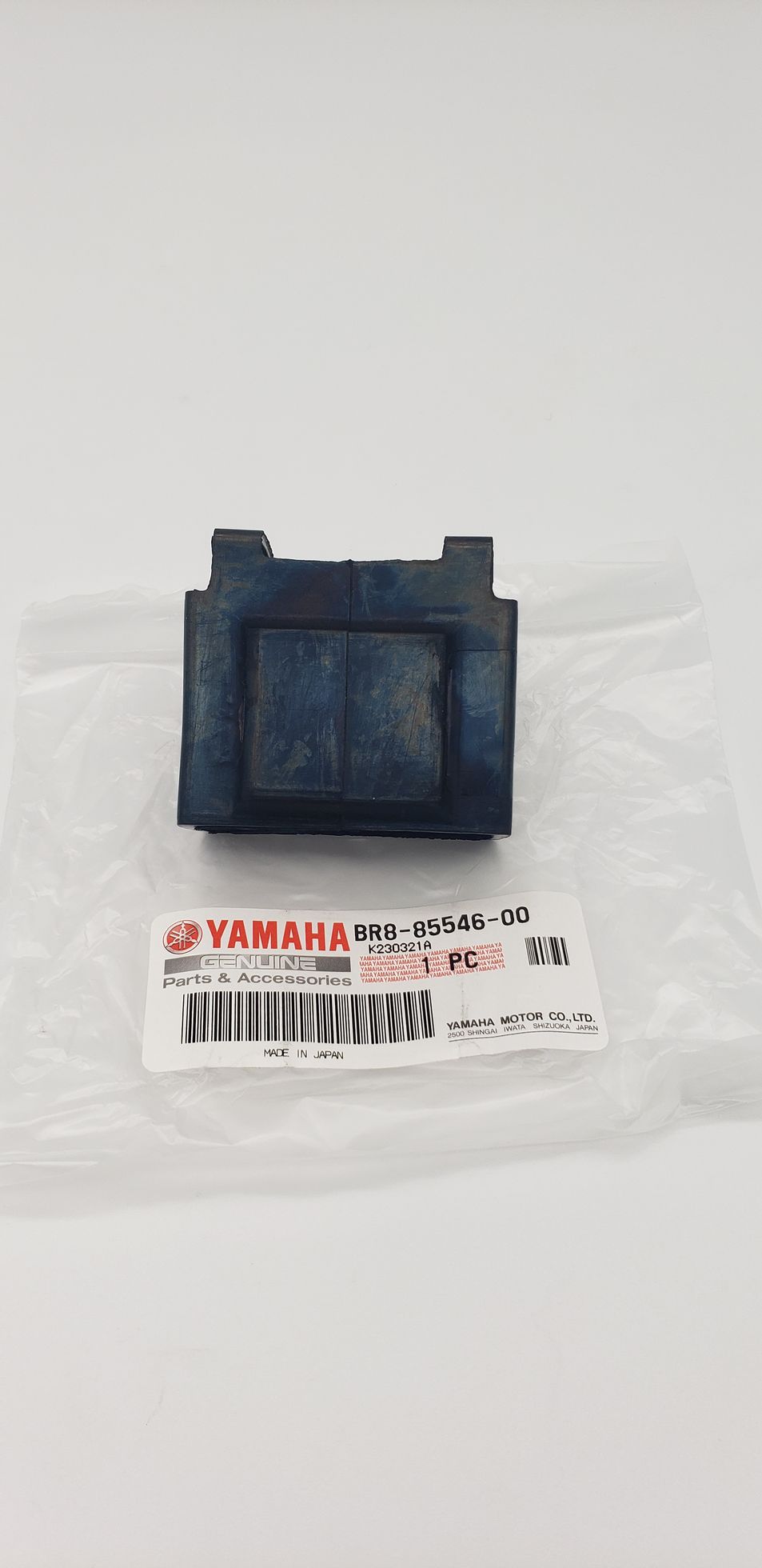 Black Yamaha motorcycle part with label, on a white surface.