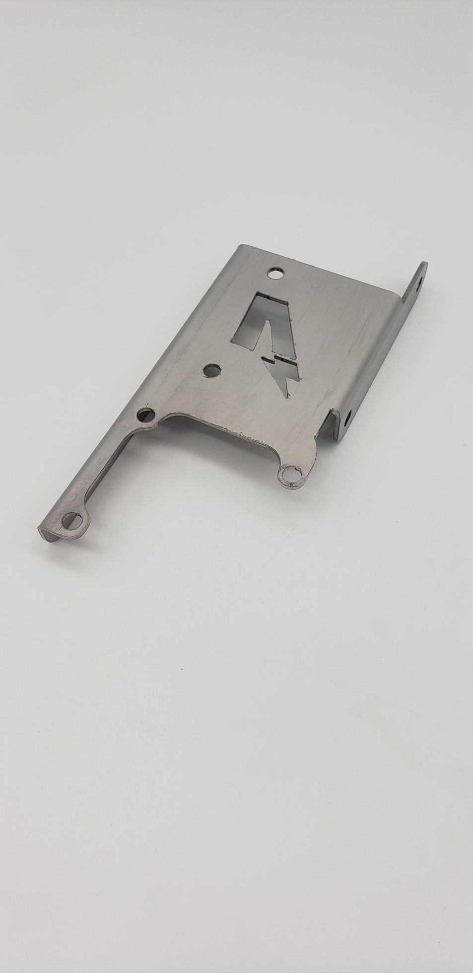 A flat, metal bracket with cutouts, including a lightning bolt shape, against a white background.