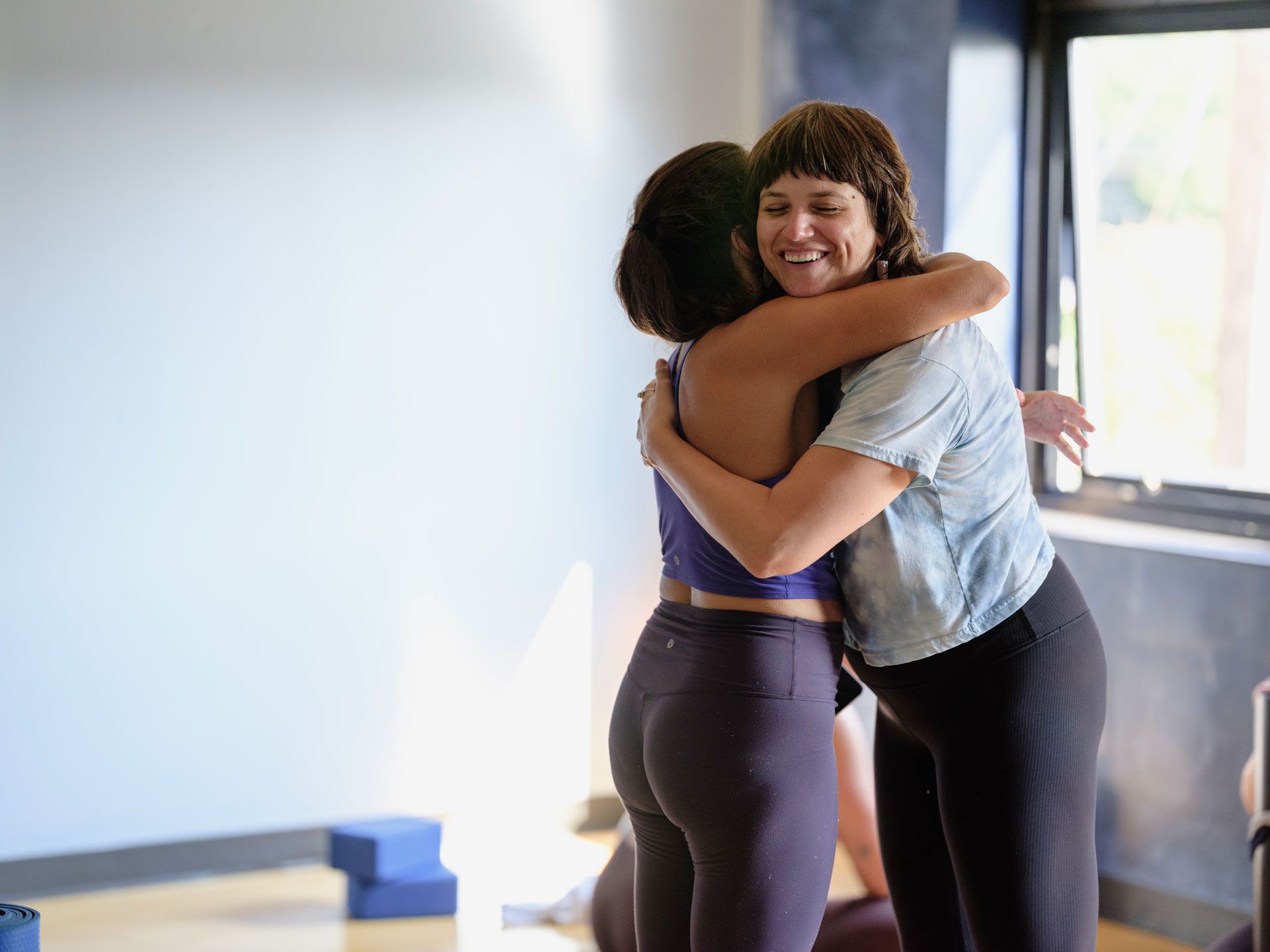 Two yoga students hugging after a class